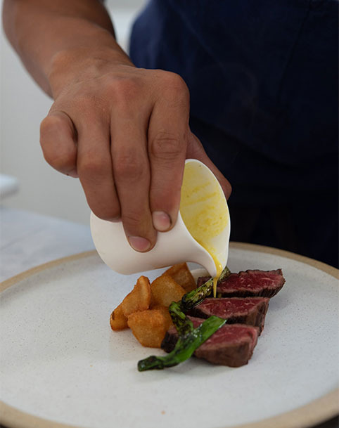 Bonbite catering chef plating a small plate of seared flank steak with crispy potatoes and jus