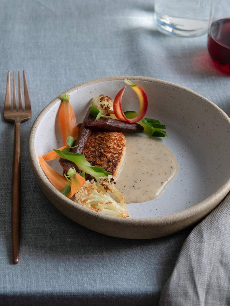 Bonbite catering plated entreé of seared snapper, heirloom carrots and cauliflower with a peppercorn cream sauce